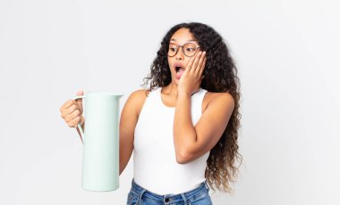 İspanyol güzel kadın mutlu, heyecanlı ve şaşırmış hissediyor ve elinde kahve termosu tutuyor.