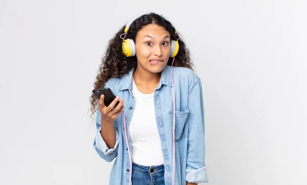 Mujer Bonita Hispana Mirando Perpleja Confundida Sosteniendo Teléfono Inteligente Auriculares —  Fotos de Stock