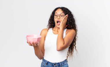 İspanyol güzel kadın mutlu, heyecanlı ve şaşırmış hissediyor ve elinde boş bir tencere tutuyor.