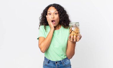 İspanyol güzel kadın şok olmuş, korkmuş ve elinde bir kurabiye şişesi tutuyor.