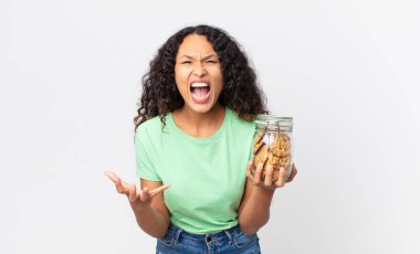 İspanyol güzel kadın kızgın, sinirli ve hayal kırıklığına uğramış görünüyor ve elinde bir kurabiye şişesi tutuyor.