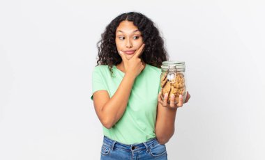 İspanyol güzel kadın düşünüyor, kuşkulu ve şaşkın hissediyor ve elinde bir kurabiye şişesi tutuyor.