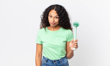 İspanyol güzel kadın şaşkın, kafası karışık ve elinde fırça tutan