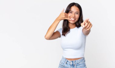 Oldukça zayıf İspanyol bir kadın sana neşeli bir şekilde gülümsüyor ve sana jest yapıyor.