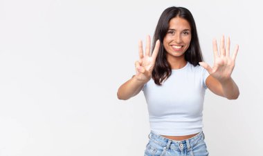 Gülümseyen ve arkadaş canlısı görünen zayıf İspanyol kadın, sekiz numarayı gösteriyor.