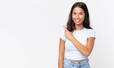 Oldukça zayıf İspanyol bir kadın neşeli bir şekilde gülümsüyor, mutlu hissediyor ve bir tarafı işaret ediyor.