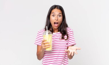 Genç İspanyol kadın şok olmuş, şaşırmış ve elinde vanilyalı bir milkshake tutuyor.