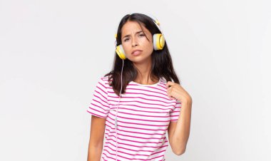 Genç İspanyol kadın stresli, endişeli, yorgun ve bıkkın kulaklıkla müzik dinliyor.