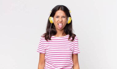 Genç İspanyol kadın iğrenmiş ve rahatsız olmuş hissediyor ve kulaklıkla müzik dinliyor.