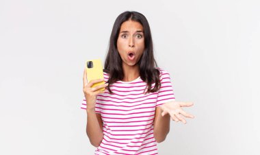 Genç İspanyol kadın, inanılmaz bir sürprizle şaşkın, şaşkın ve afallamış ve elinde akıllı bir telefon tutuyordu.