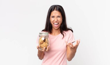 Genç İspanyol kadın kızgın, sinirli ve hayal kırıklığına uğramış görünüyor ve elinde cam bir kurabiye şişesi tutuyor.