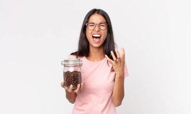 Genç İspanyol kadın umutsuz, sinirli ve stresli görünüyor ve elinde kahve şişesi tutuyor.