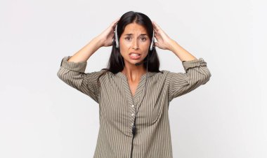 Genç İspanyol kadın stresli, endişeli ya da korkmuş hissediyor, elleri kulaklıklı. tele pazarlama kavramı