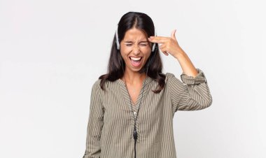 Genç İspanyol kadın mutsuz ve stresli görünüyor, intihar jesti kulaklıkla silah işareti yapıyor. tele pazarlama kavramı