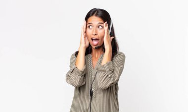 Genç İspanyol kadın mutlu, heyecanlı ve kulaklıkla şaşırmış hissediyor. tele pazarlama kavramı