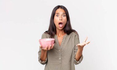 Genç İspanyol kadın şok olmuş ve şaşırmış hissediyor ve elinde boş bir kâse ya da esrar tutuyor.