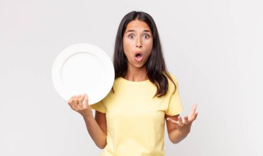 Genç İspanyol kadın şok olmuş, şaşırmış ve elinde boş bir tabak tutuyor.