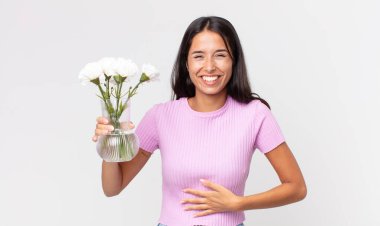 Süslü çiçekleri tutan komik bir şakaya gülen genç İspanyol kadın.