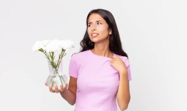 Genç İspanyol kadın kendini stresli, endişeli, yorgun ve hayal kırıklığına uğramış hissediyor. Elinde süslü çiçekler tutuyor.