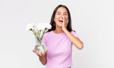 Genç İspanyol kadın kendini mutlu hissediyor, elleri ağzının yanında süs çiçekleri tutan büyük bir çığlık atıyor.