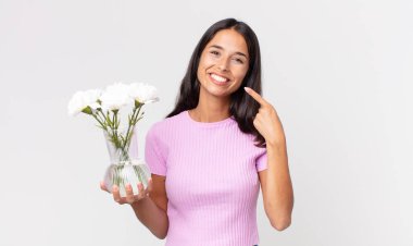 Süslü çiçekleri tutan, kendine güvenen genç İspanyol kadın.