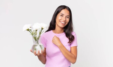 Genç İspanyol kadın kendini mutlu hissediyor ve bir meydan okumayla yüzleşiyor ya da dekoratif çiçekleri tutmasını kutluyor