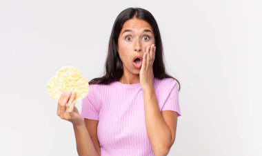 Genç İspanyol kadın şok olmuş, korkmuş ve elinde pirinç kurabiyesi tutuyormuş. diyet kavramı