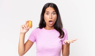 Genç İspanyol kadın şok olmuş, şaşırmış ve elinde pil tutuyor.