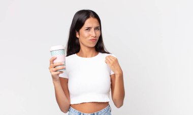 Genç İspanyol kadın kibirli, başarılı, pozitif ve gururlu görünüyor ve elinde bir kahve kabı tutuyor.