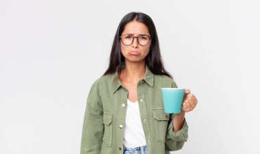 Genç İspanyol kadın üzgün ve mızmızlanıyor. Mutsuz bakıyor, ağlıyor ve elinde kahve fincanı tutuyor.