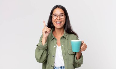 Genç İspanyol kadın bir fikri fark edip elinde kahve fincanı tutarak mutlu ve heyecanlı bir dahi gibi hissediyor.