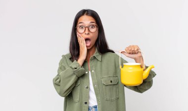 Genç İspanyol kadın şok olmuş, korkmuş ve elinde bir çaydanlık tutuyor.