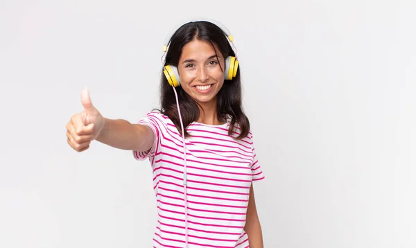 若いヒスパニック系の女性は誇りを感じます ヘッドフォンで音楽を聞いて親指アップ積極的に笑顔 — ストック写真