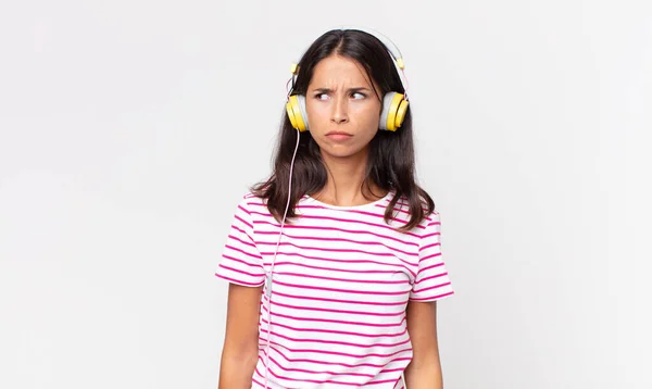 若いヒスパニック系の女性は悲しい 動揺や怒りを感じ ヘッドフォンで音楽を聞いている側を見て — ストック写真