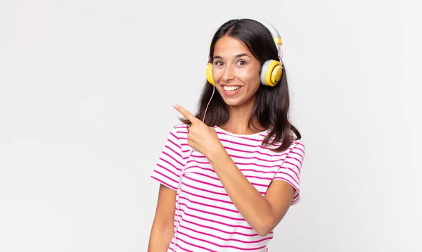 ヘッドフォンで音楽を聴いている側を見て興奮して驚いている若いヒスパニック系の女性 — ストック写真