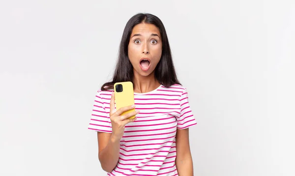 Mujer Hispana Joven Mirando Muy Sorprendido Sorprendido Sosteniendo Teléfono Inteligente —  Fotos de Stock