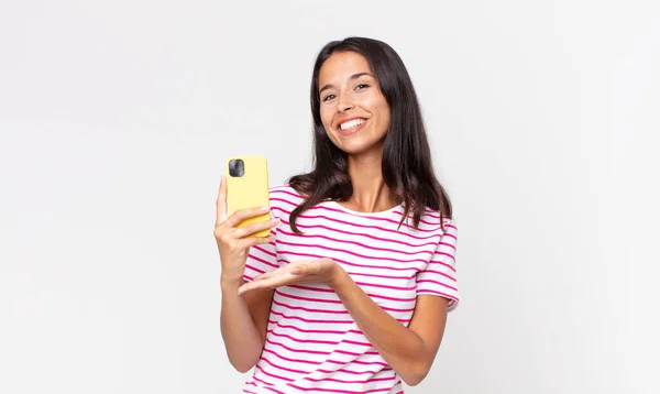若いヒスパニック系の女性が笑顔で幸せを感じコンセプトを示しスマートフォンを持っています — ストック写真