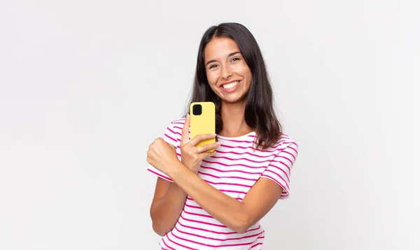 若いヒスパニック系の女性は幸せを感じ 挑戦やお祝いに直面し スマートフォンを保持します — ストック写真