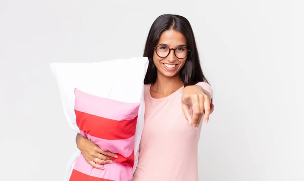 若いヒスパニック系の女性がカメラを向けパジャマを着て枕を持って — ストック写真