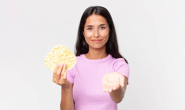 若いヒスパニック系の女性は喜んで優しいと笑みを浮かべて提供し コンセプトを示し 米クッキーを保持します 食事のコンセプト — ストック写真