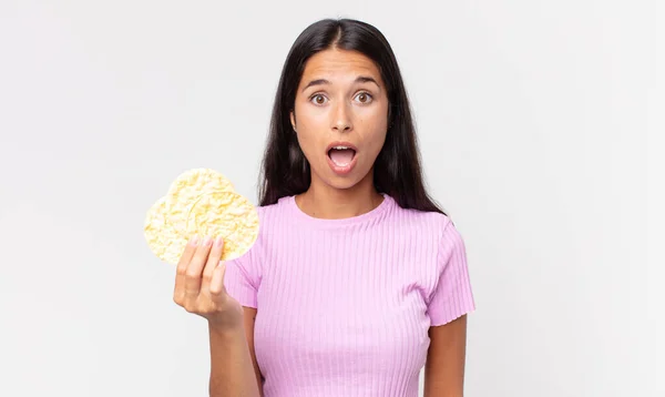 Молодая Испаноязычная Женщина Выглядит Шокированной Удивленной Держит Рисовое Печенье Концепция — стоковое фото