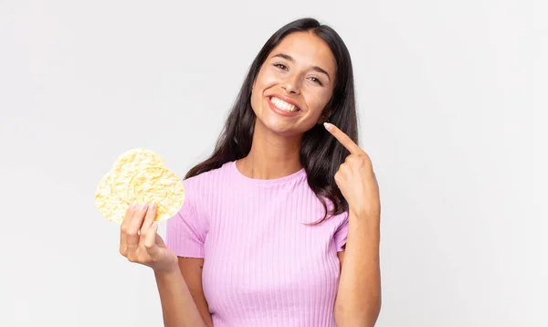 若いヒスパニック系の女性が自信を持って笑顔を指摘し 米クッキーを保持します 食事のコンセプト — ストック写真