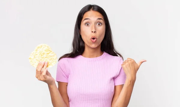 若いヒスパニック系の女性は不信感に驚き米クッキーを持っている 食事のコンセプト — ストック写真