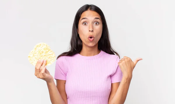 Joven Mujer Hispana Mirando Asombrada Incredulidad Sosteniendo Una Galleta Arroz — Foto de Stock