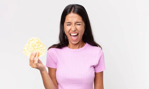 年轻的惊慌失措的女人大喊大叫 看上去很生气 手里拿着一块米糕 饮食概念 — 图库照片