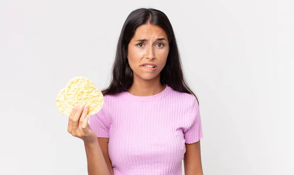 Jonge Spaanse Vrouw Kijkt Verbaasd Verward Houdt Een Rijstkoekje Vast — Stockfoto