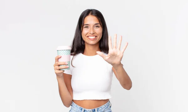年轻的惊慌失措的女人面带微笑 显得和蔼可亲 露出五号牌 拿着一个装咖啡的容器 — 图库照片