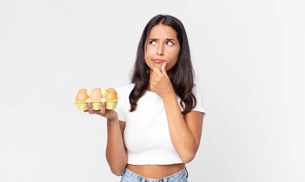 Młoda Latynoska Kobieta Myśląca Wątpiąca Zdezorientowana Trzymająca Pudełko Jajkami — Zdjęcie stockowe