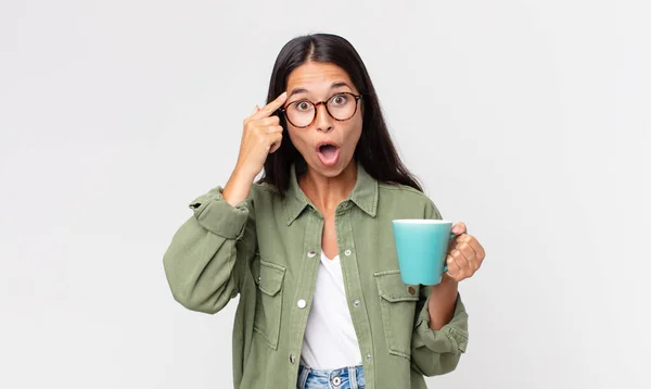 若いヒスパニック系の女性は驚いて新しい考えやアイデアやコンセプトを実現しコーヒーマグカップを保持 — ストック写真