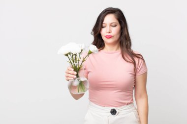 Güzel bir kadın üzgün, üzgün ya da kızgın hissediyor ve elinde dekoratif bir saksı tutuyor.